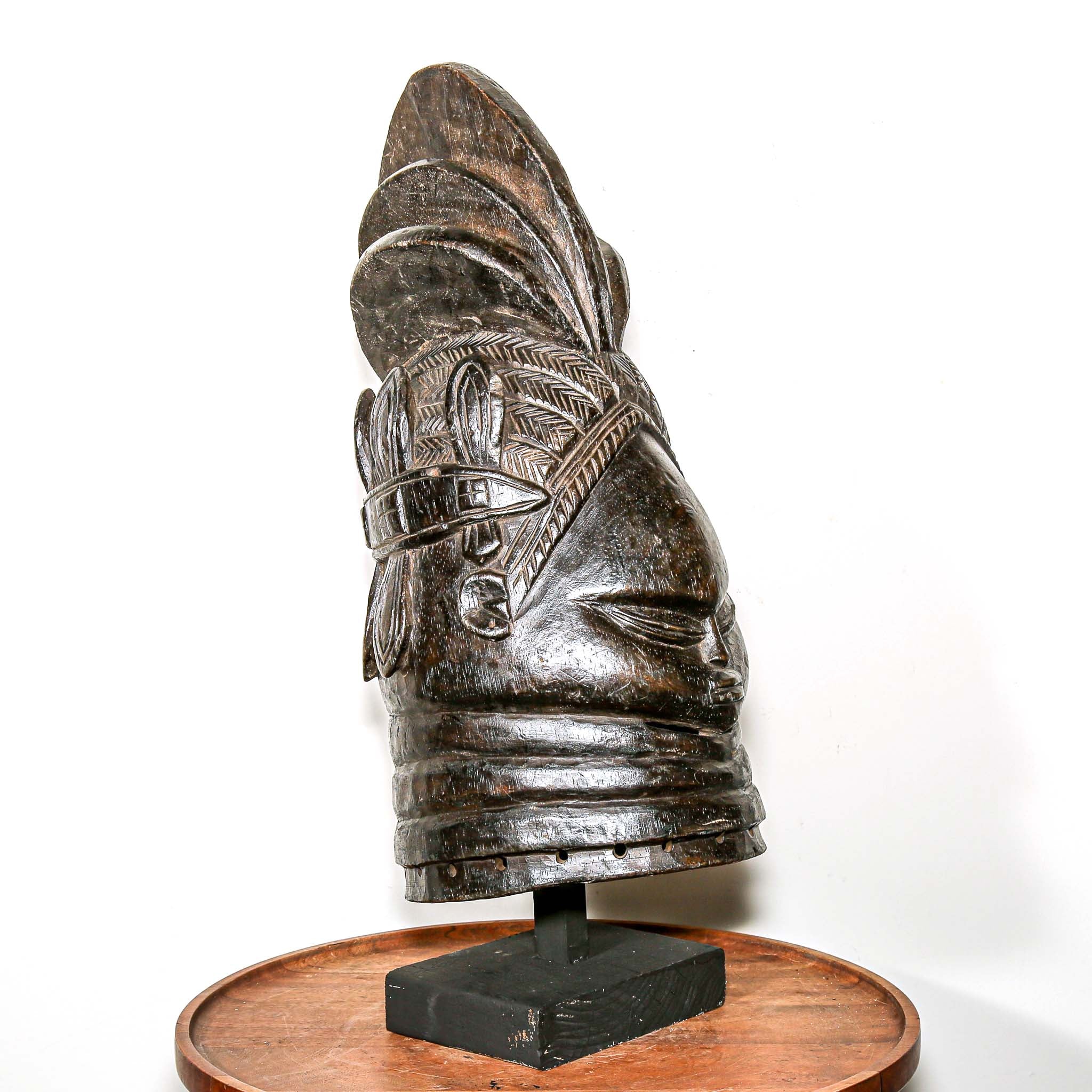 Decorative black african mask on a wooden home side table against a white background