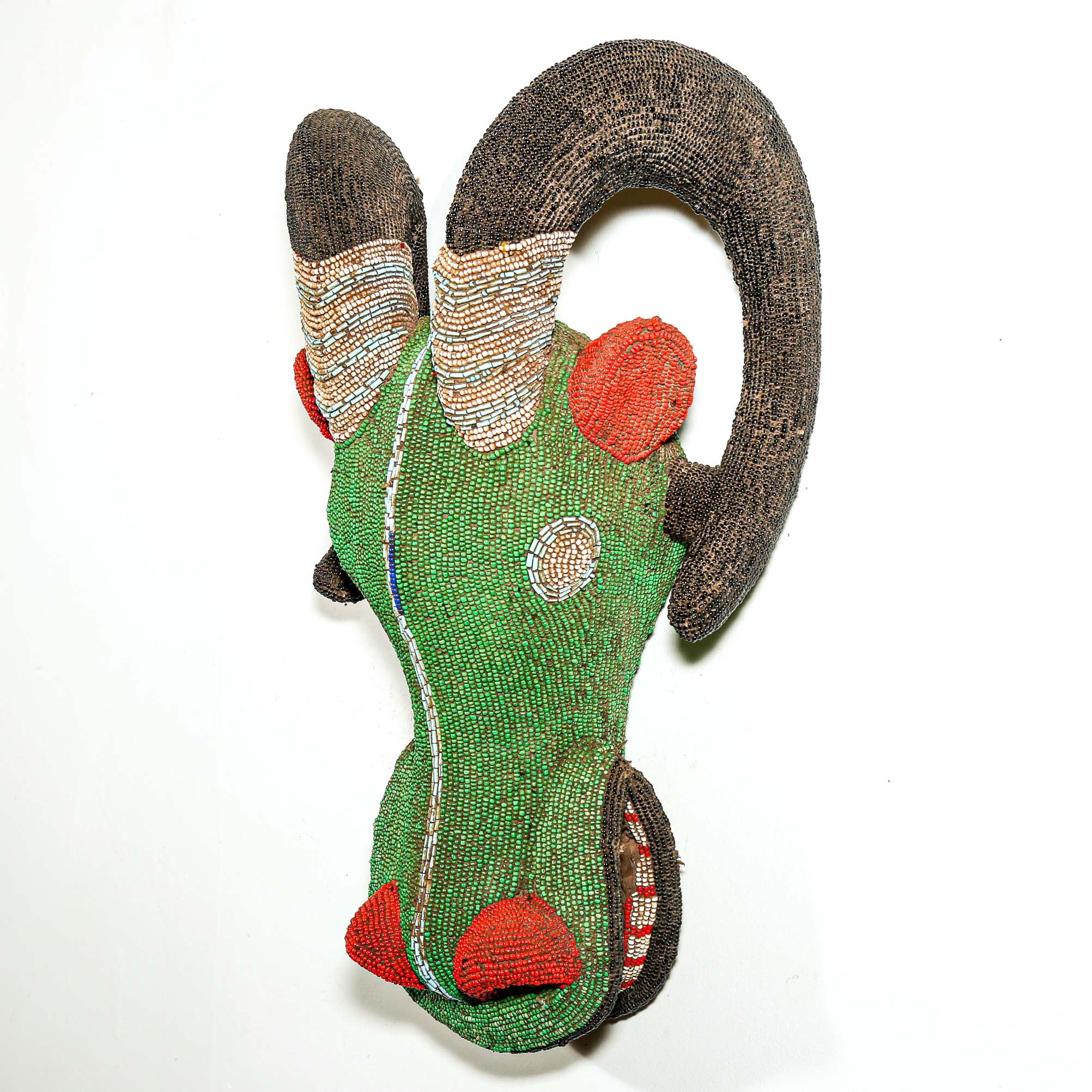 Decorative headpiece with green body, brown horns, and red accents on a white background