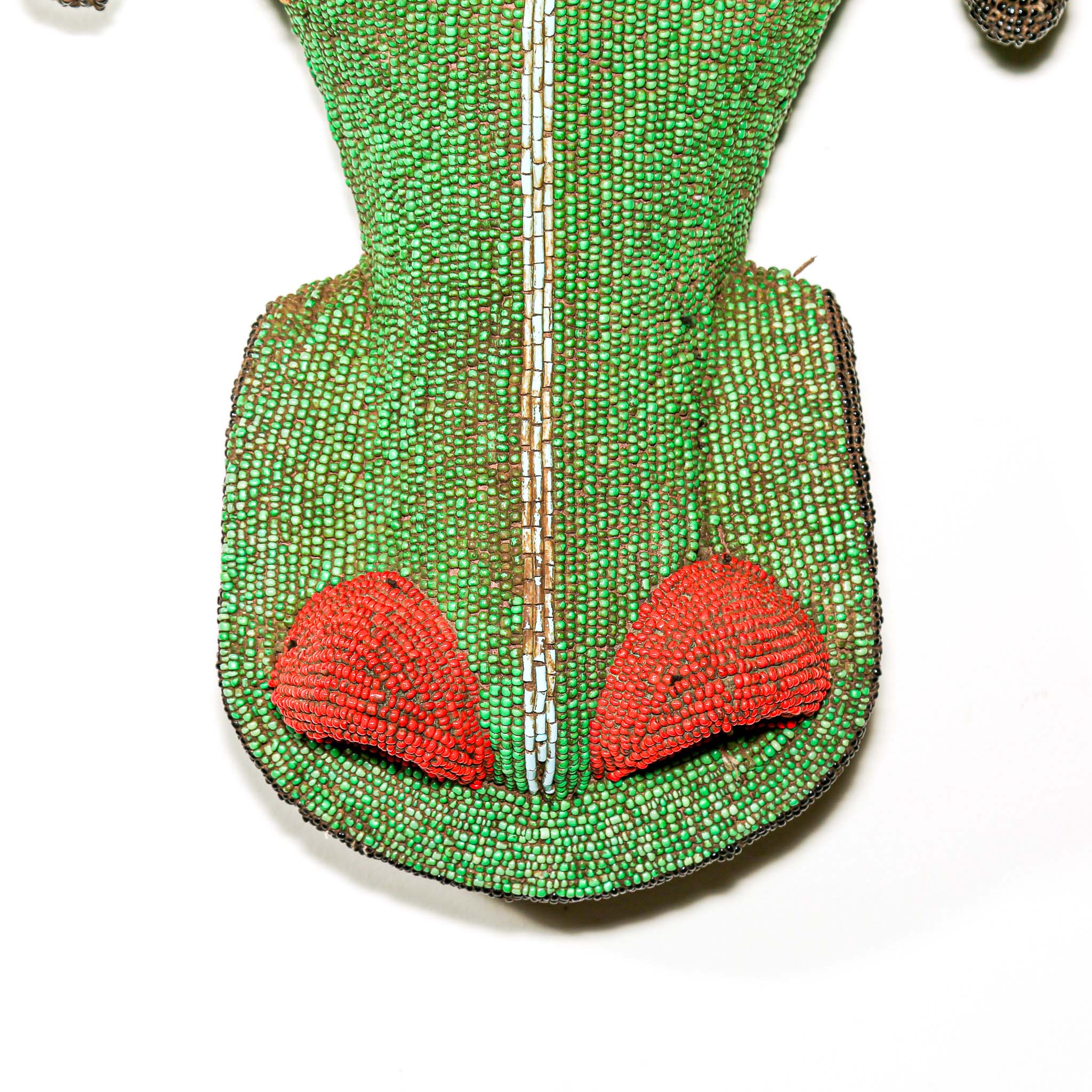Green beaded African art with red accents on a white background