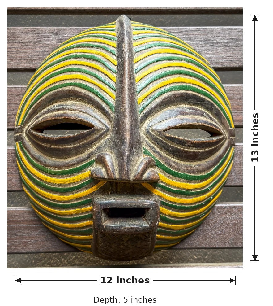 Congolese Songye Kifwebe mask with circular proportions, carved facial features, and vivid yellow and green geometric stripes