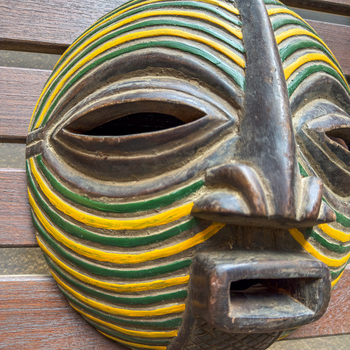 Hand-carved Songye Kifwebe face mask from Congo with bright green and yellow patterns and strong sculptural details