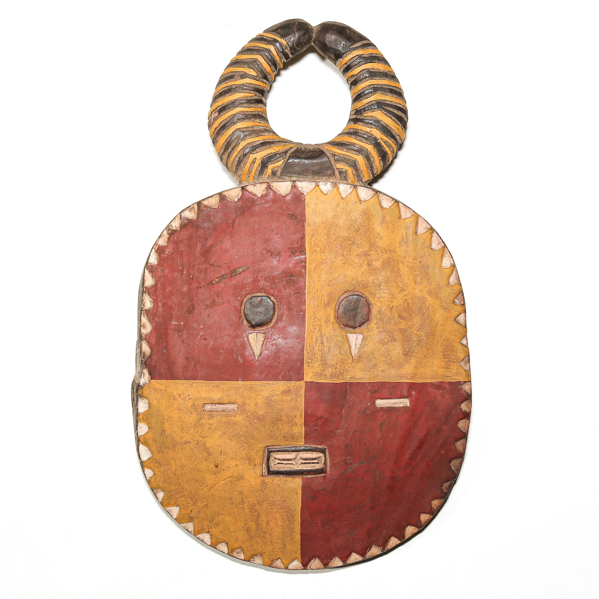 A hand-carved African wooden mask with a four-color quadrilobe face in red and ochre yellow, featuring a striped handle and small triangular eye details.