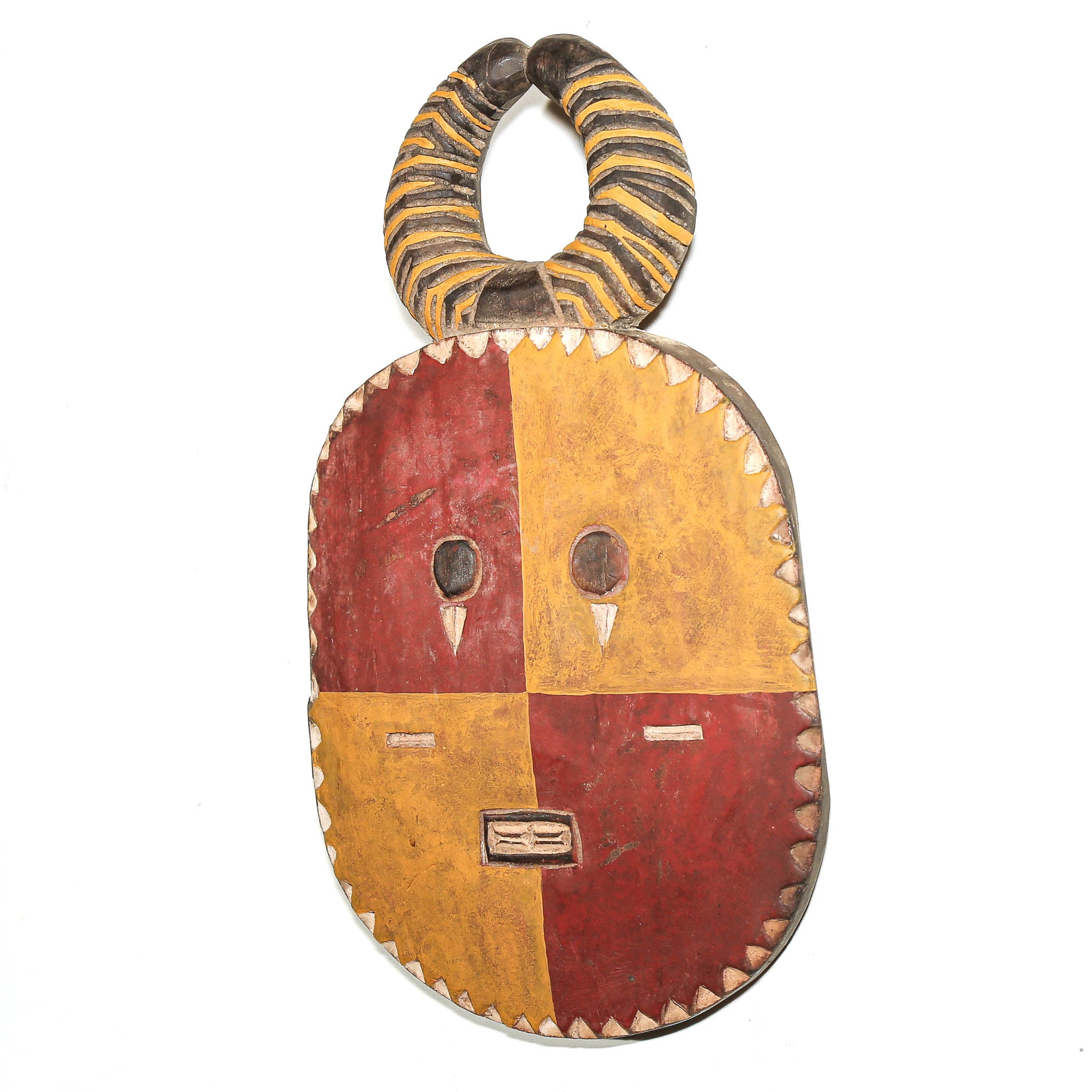 A handcrafted African wooden mask with a curved horn-like top, featuring a four-quadrant face painted in alternating red and ochre yellow sections, with carved eye sockets and a small rectangular mouth panel.