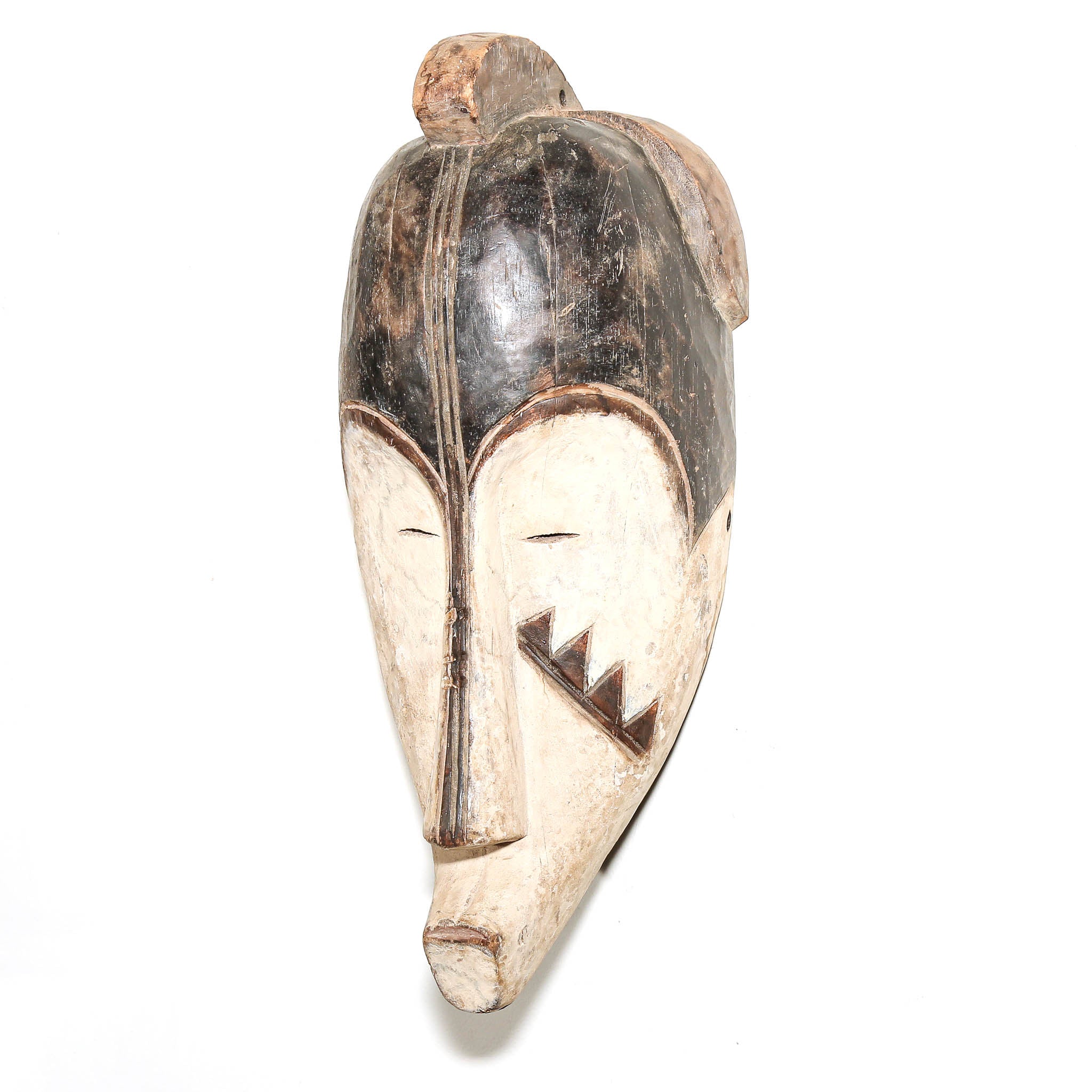 A hand-carved wooden African-style mask with a long snout, painted black hair, and a geometric triangular mouth design, shown against a plain white background.