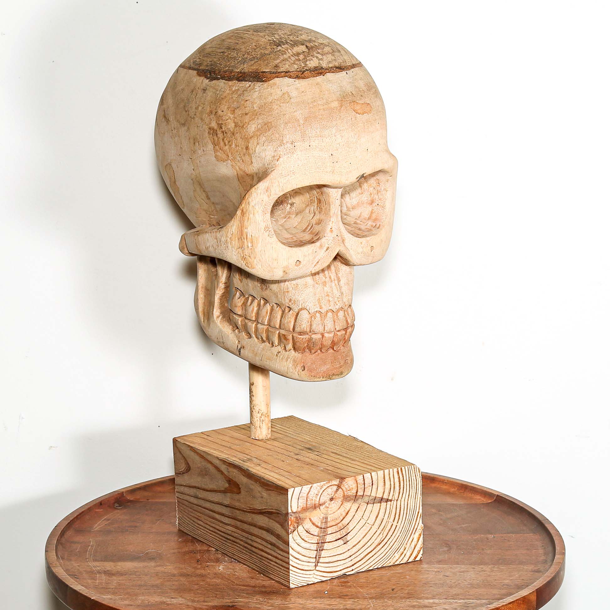 Wooden Skull sculpture on a stand with a white background made in Africa