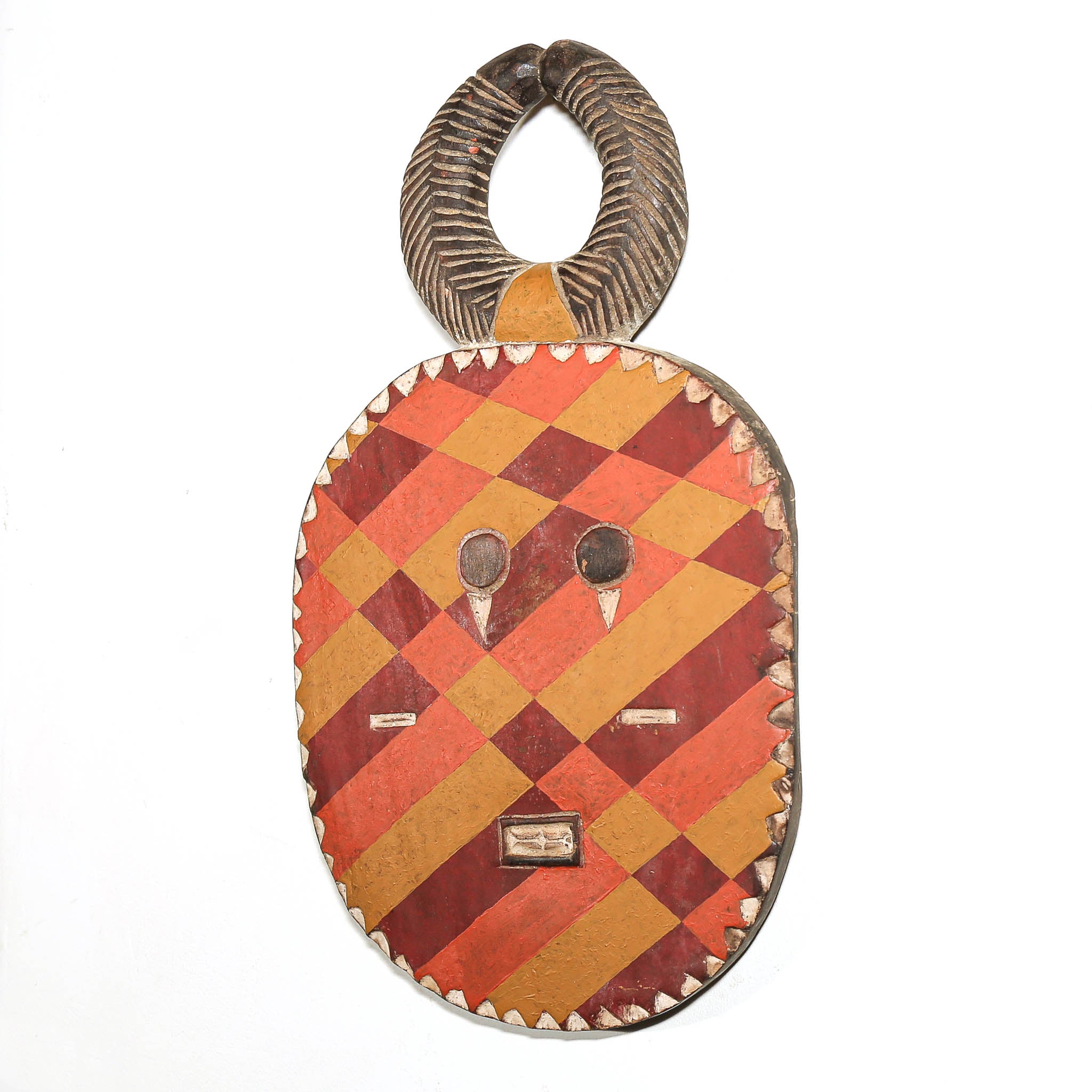 A hand-carved African wooden mask with a patterned red and orange face and a textured dark brown handle, shown against a plain white background.