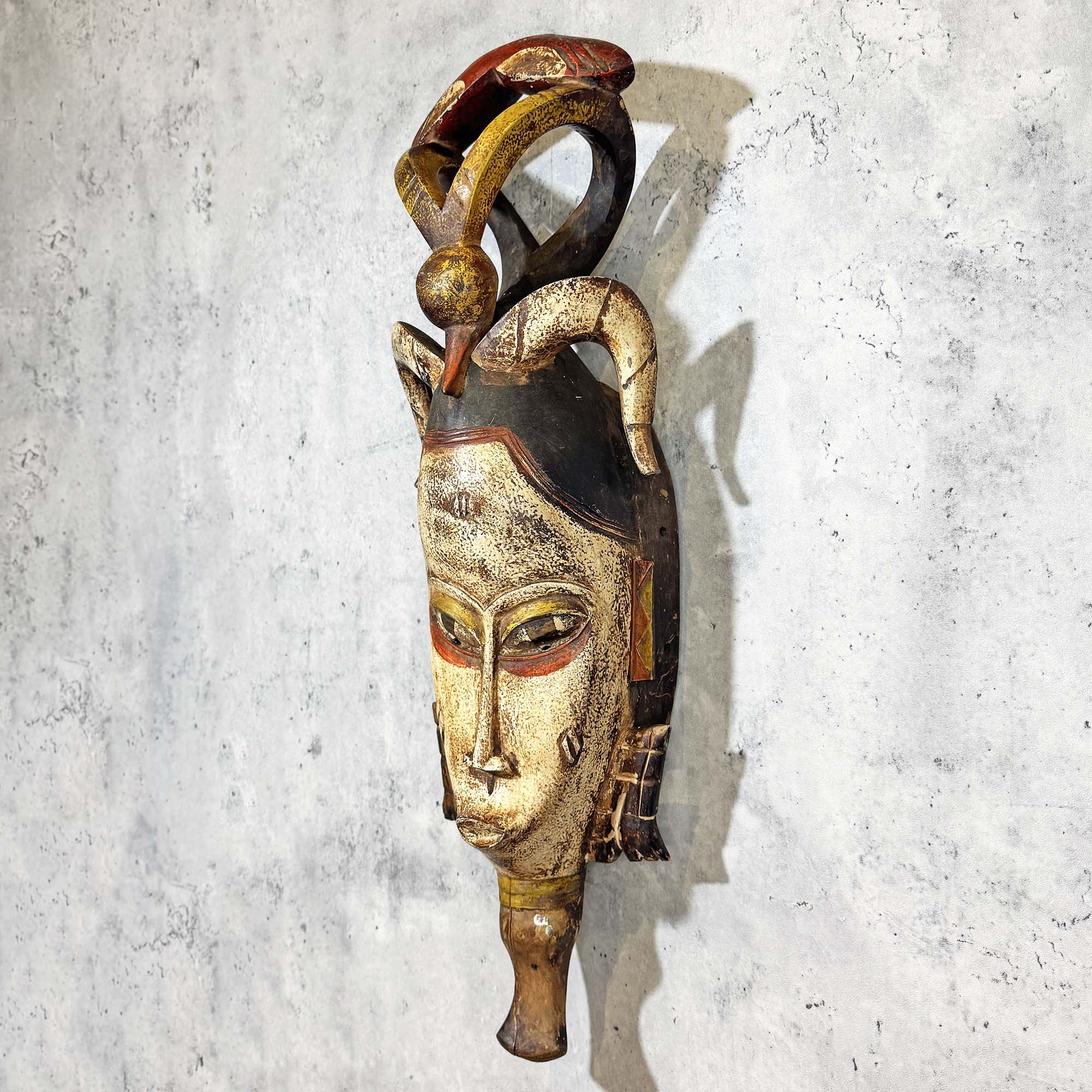 Left side of Guro Mask from Côte d'Ivoire hanging on a wall as a decoration