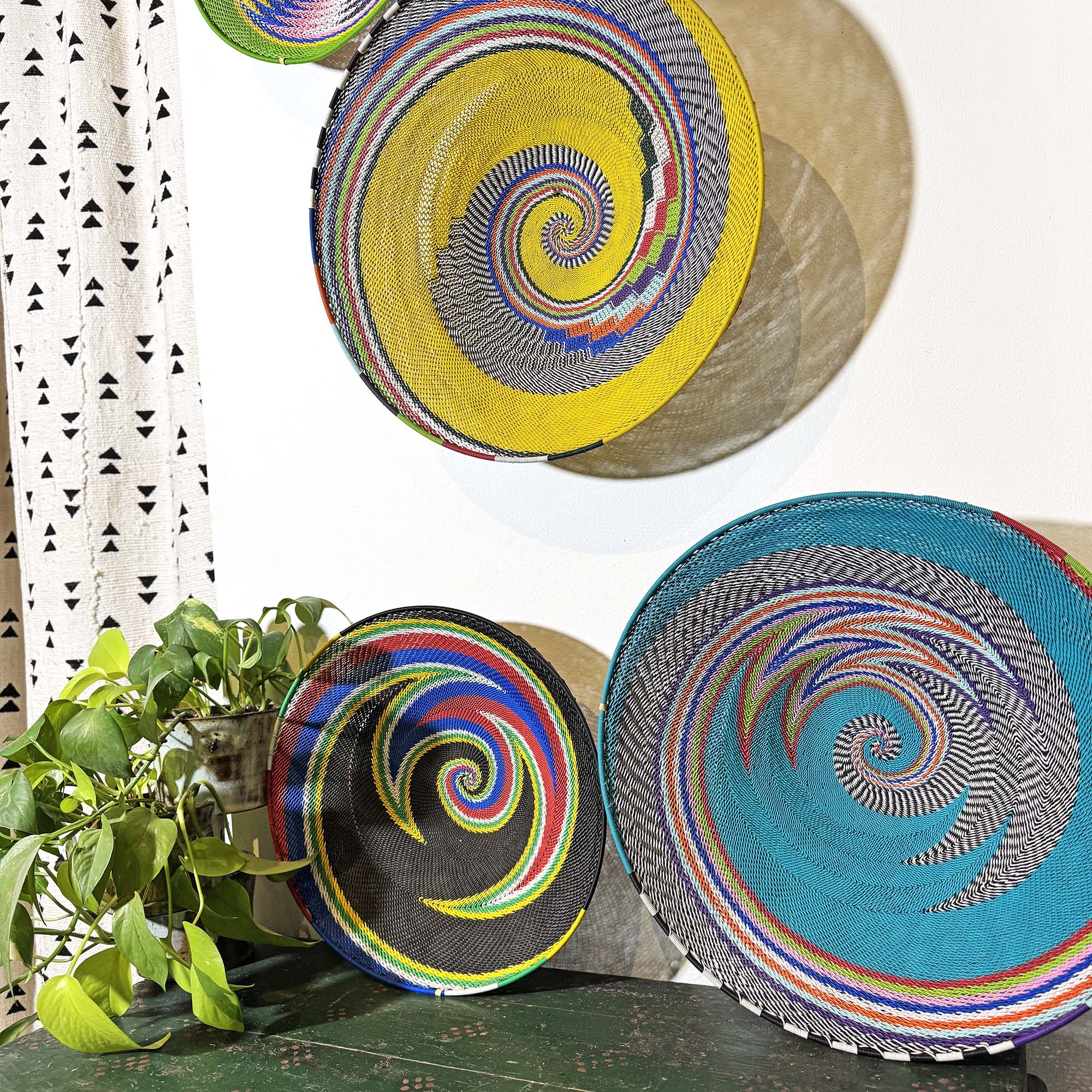 Zulu Wire Baskets from South Africa hanging on a wall with other color baskets