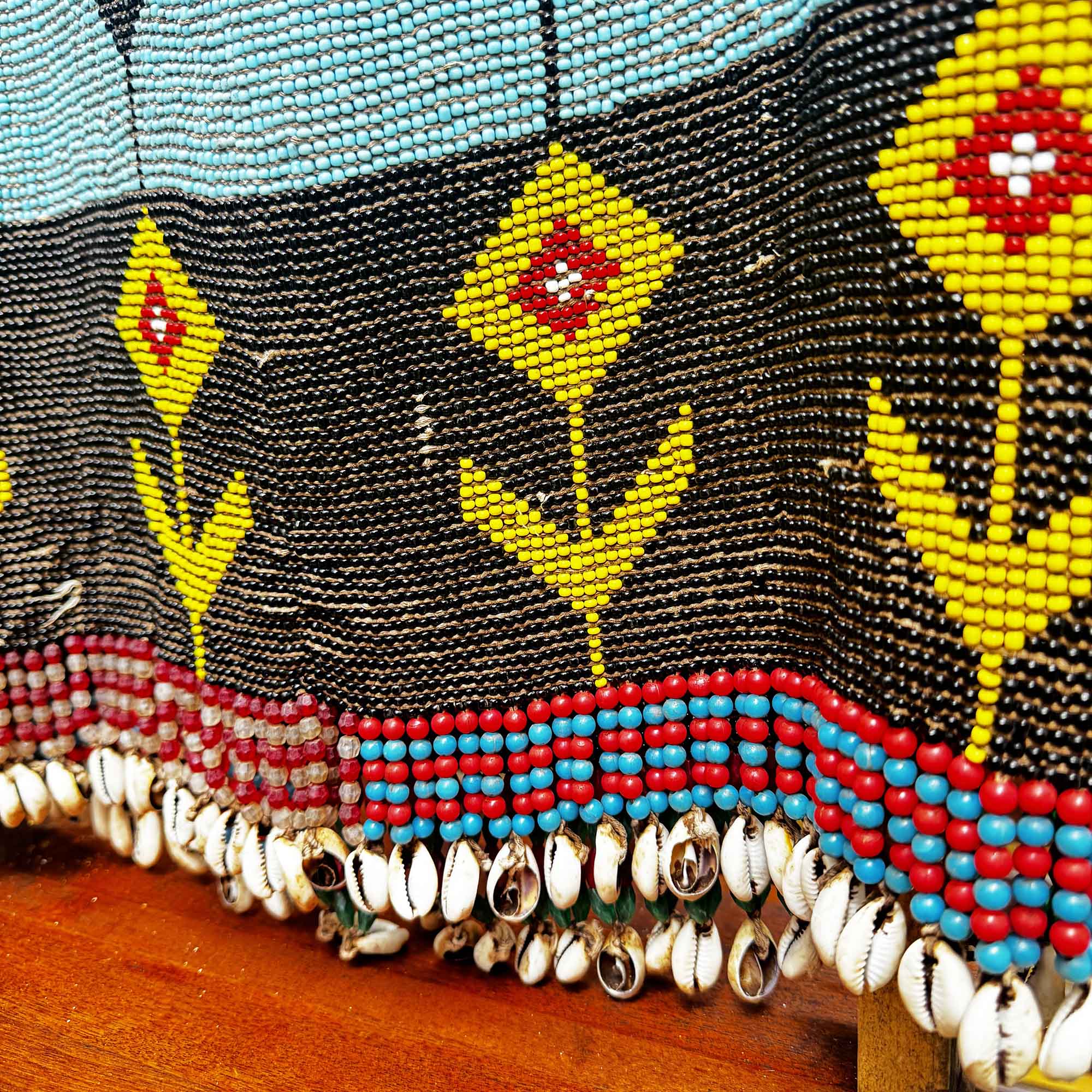 Close-up of a beaded african shirt with shells and with geometric patterns on a wooden surface