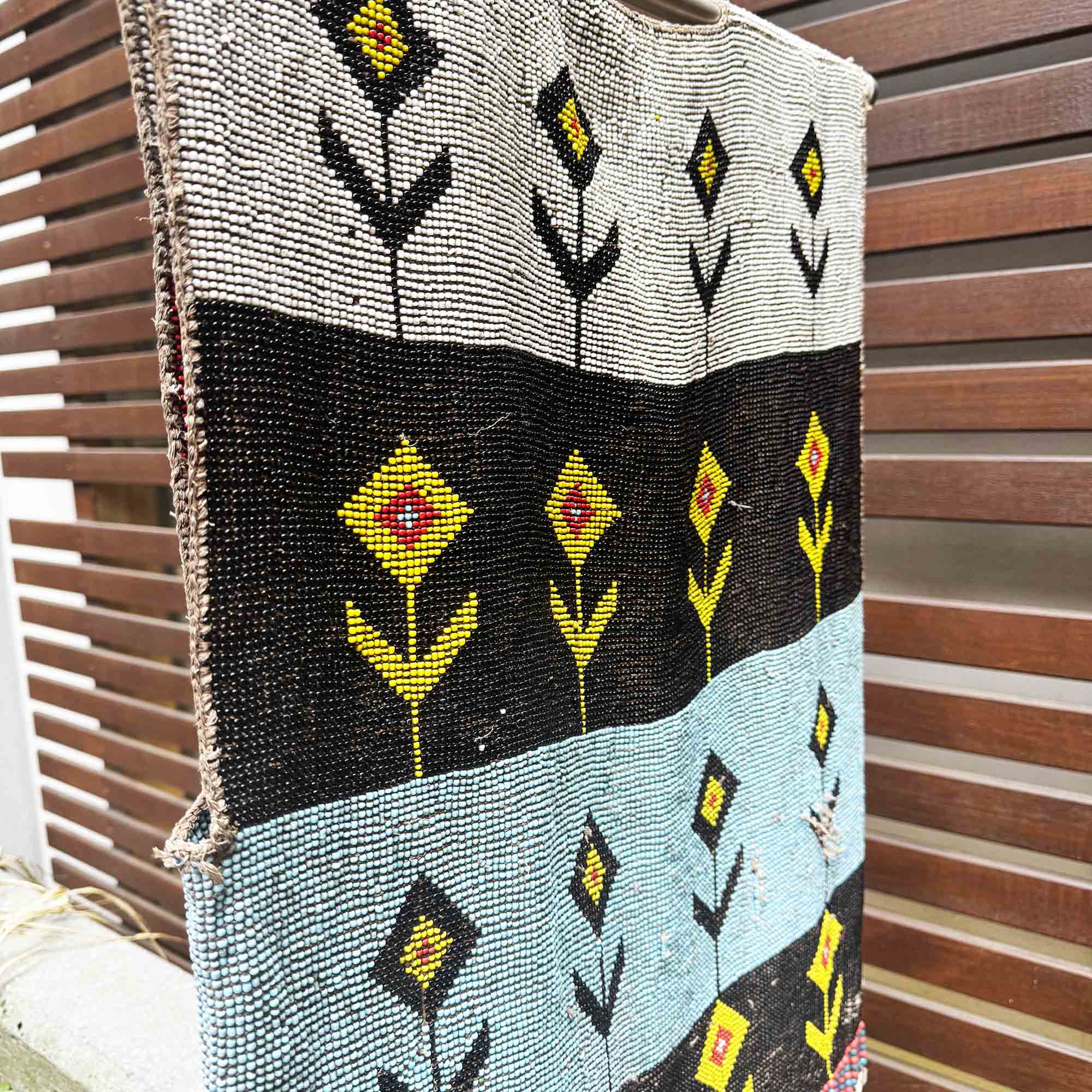 Textile with geometric floral patterns hanging against a wooden background