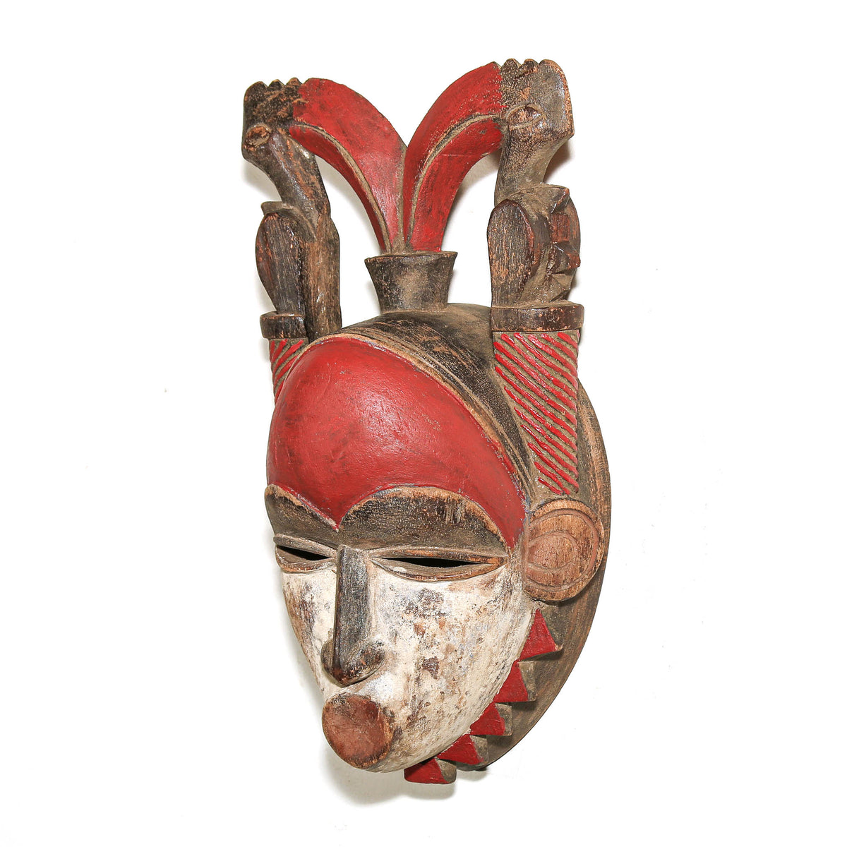 Hand-carved Baule tribal mask with red surface, elongated face, and traditional Ivory Coast styling