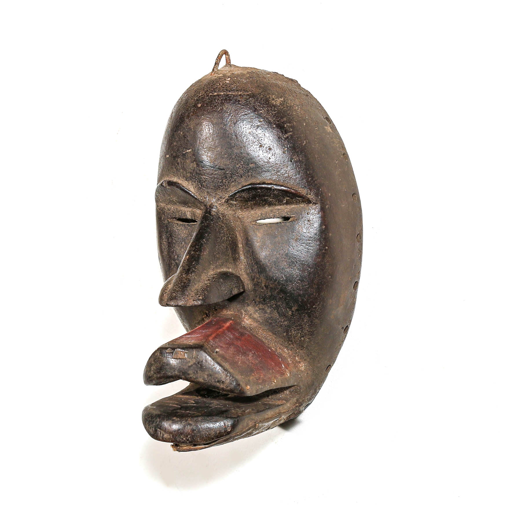 A black carved wooden mask with a protruding tongue, shown against a plain white background.
