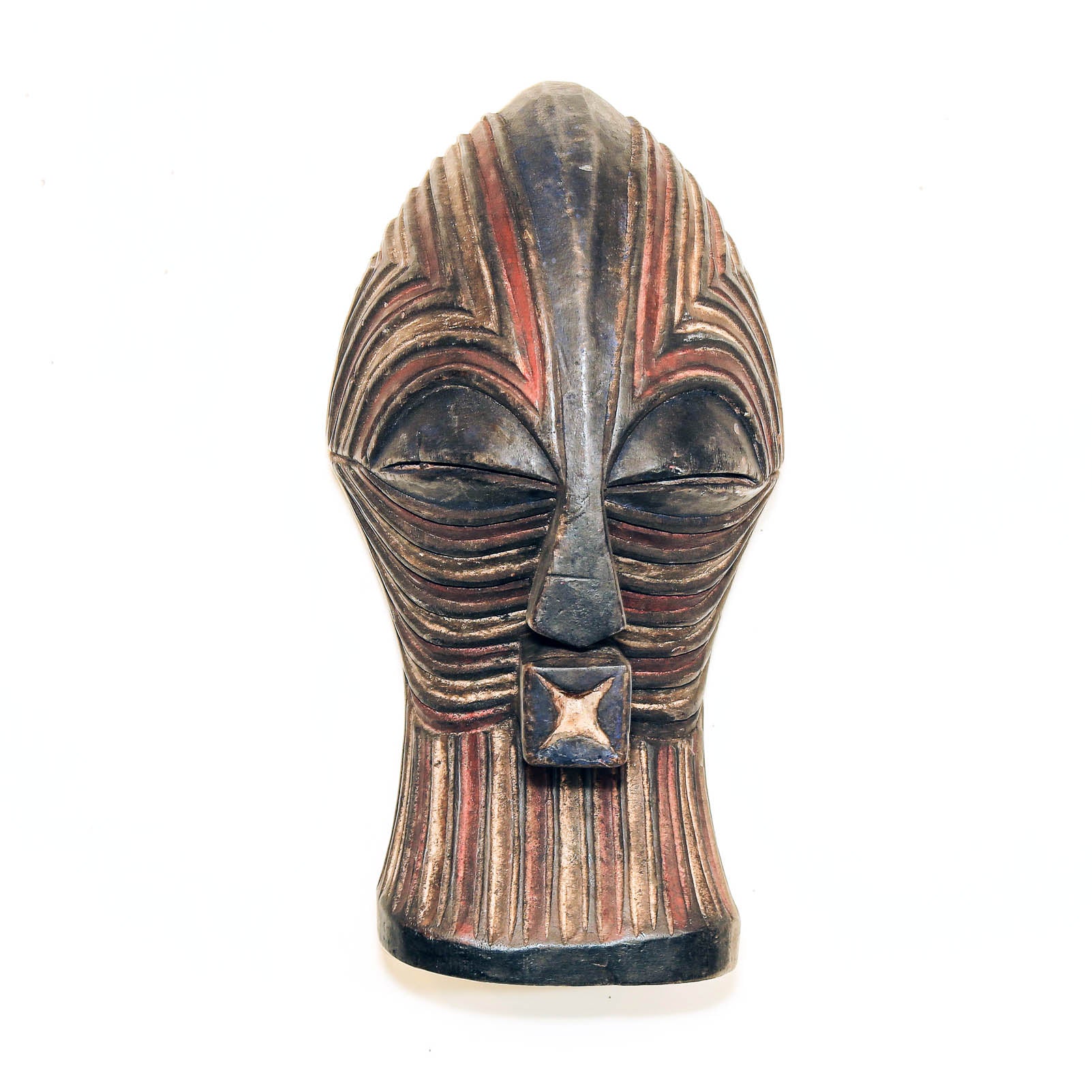 A carved African-style wooden mask head with closed eyes, featuring carved horizontal ridges and painted black, brown, and red details, set against a plain white background.