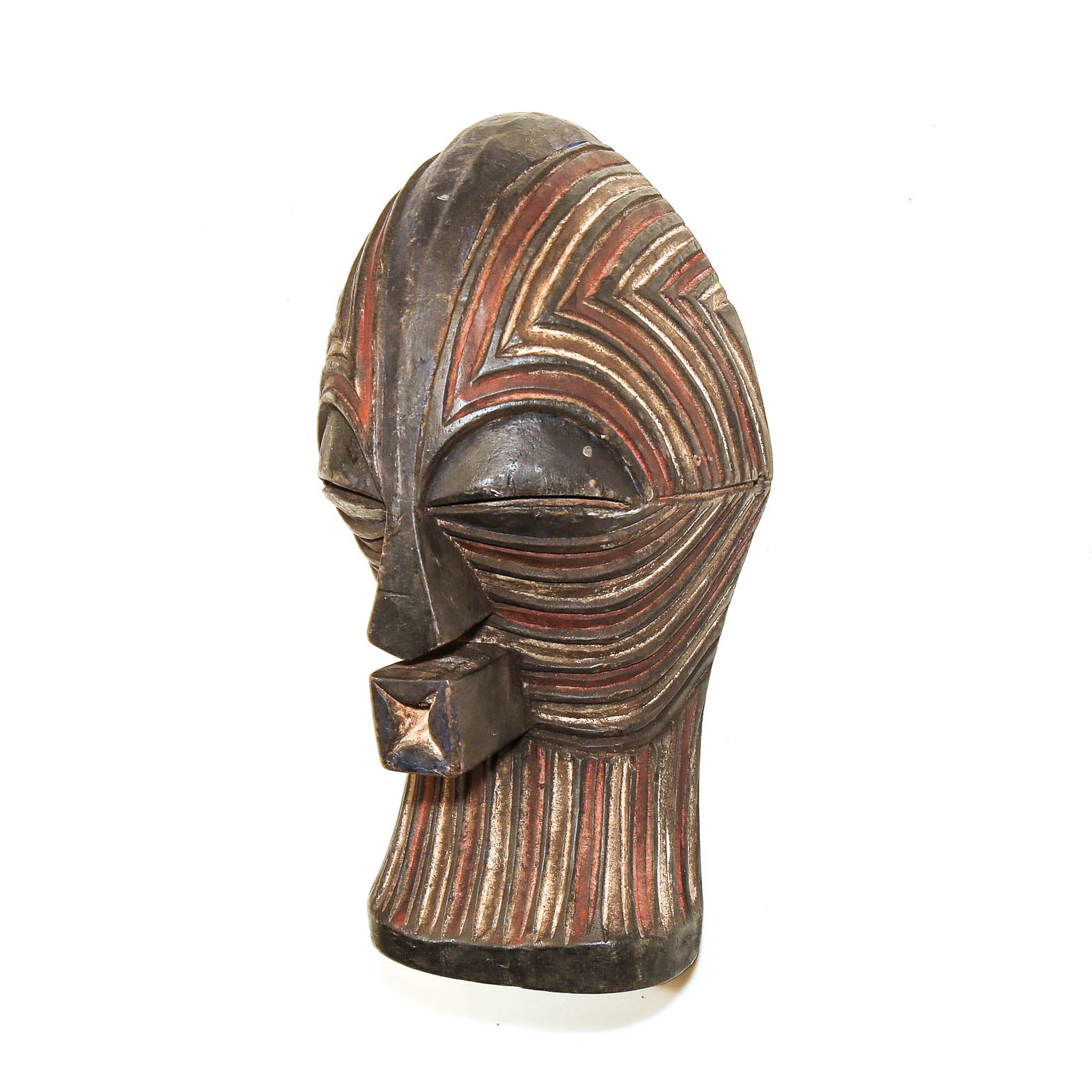 A carved African-style wooden mask head with geometric striped patterns in dark brown, black, and reddish-brown tones, shown against a plain white background.