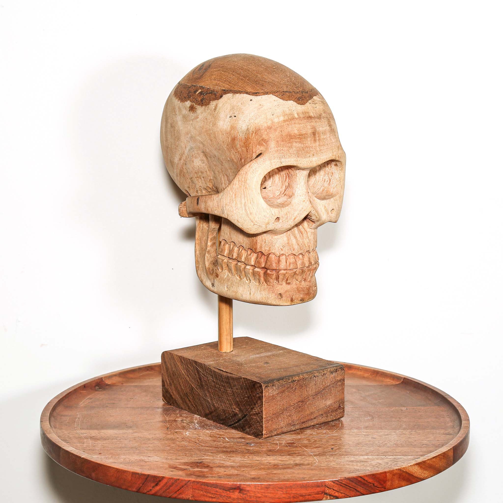 Hand Carved African Wooden human skull sculpture on a wooden base in a living room on a side table