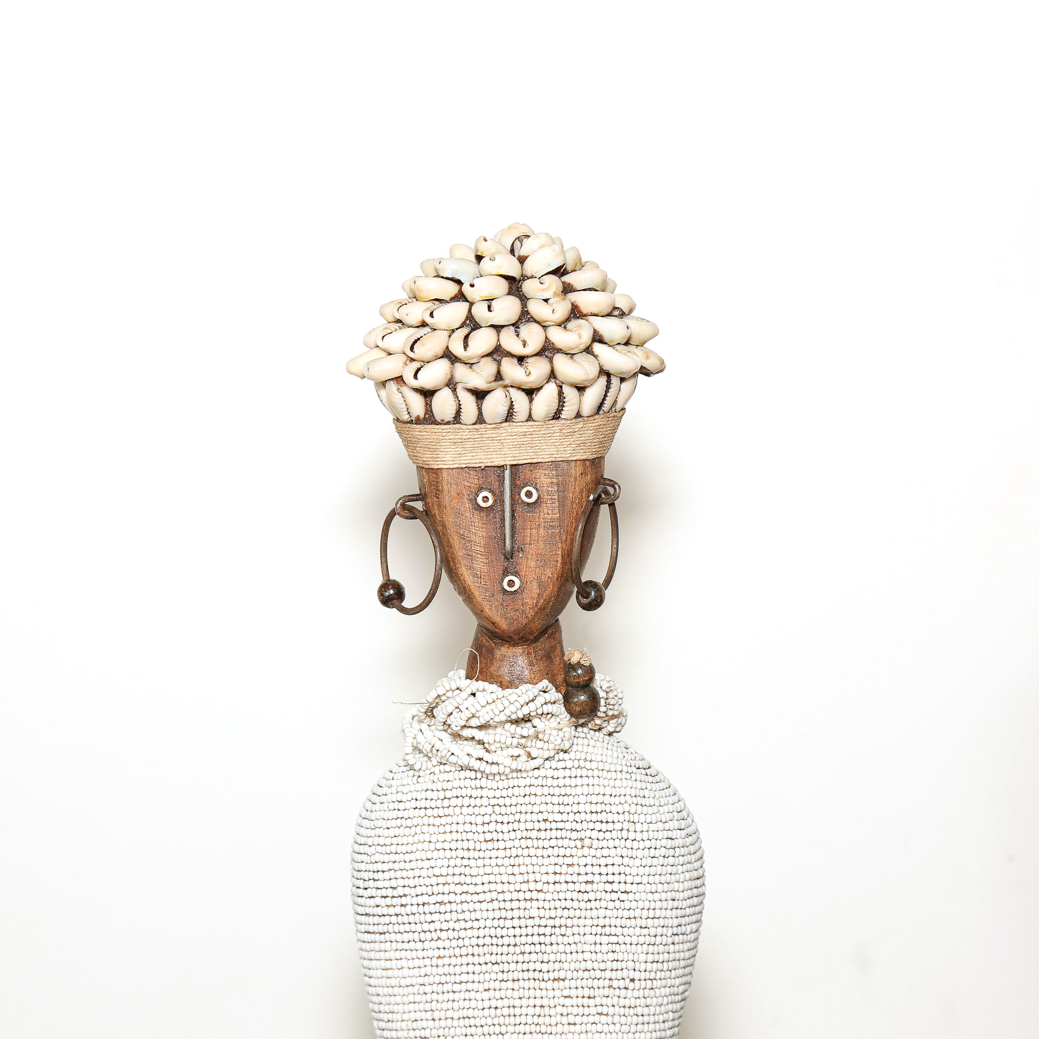 A handmade African-style wooden figurine of a woman with a woven basket head, decorated with cowrie shells, a wooden mask face, and a knotted rope neck, set against a plain white background.