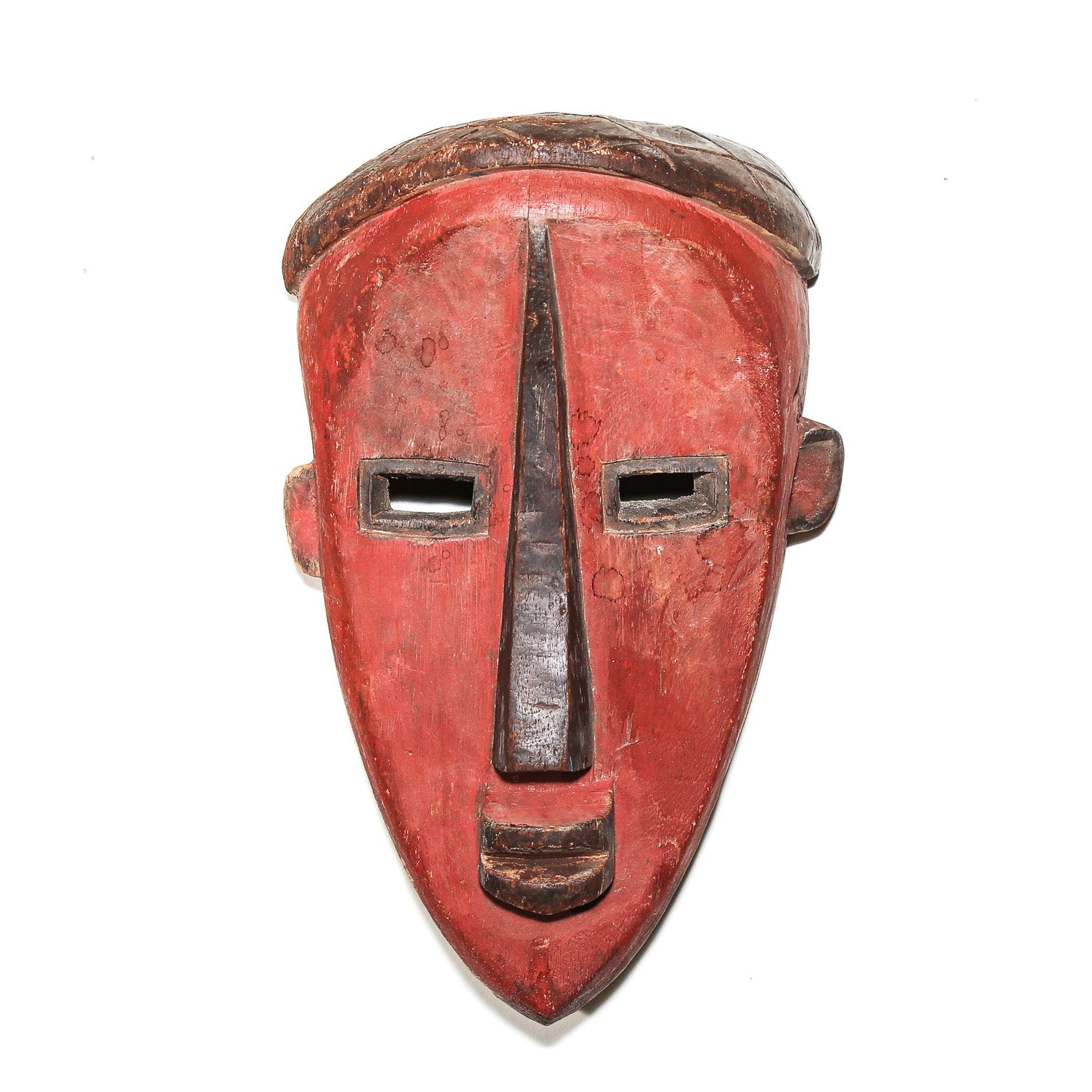 A hand-carved African wooden mask with a red-painted face and dark brown accents, shown against a plain white background.