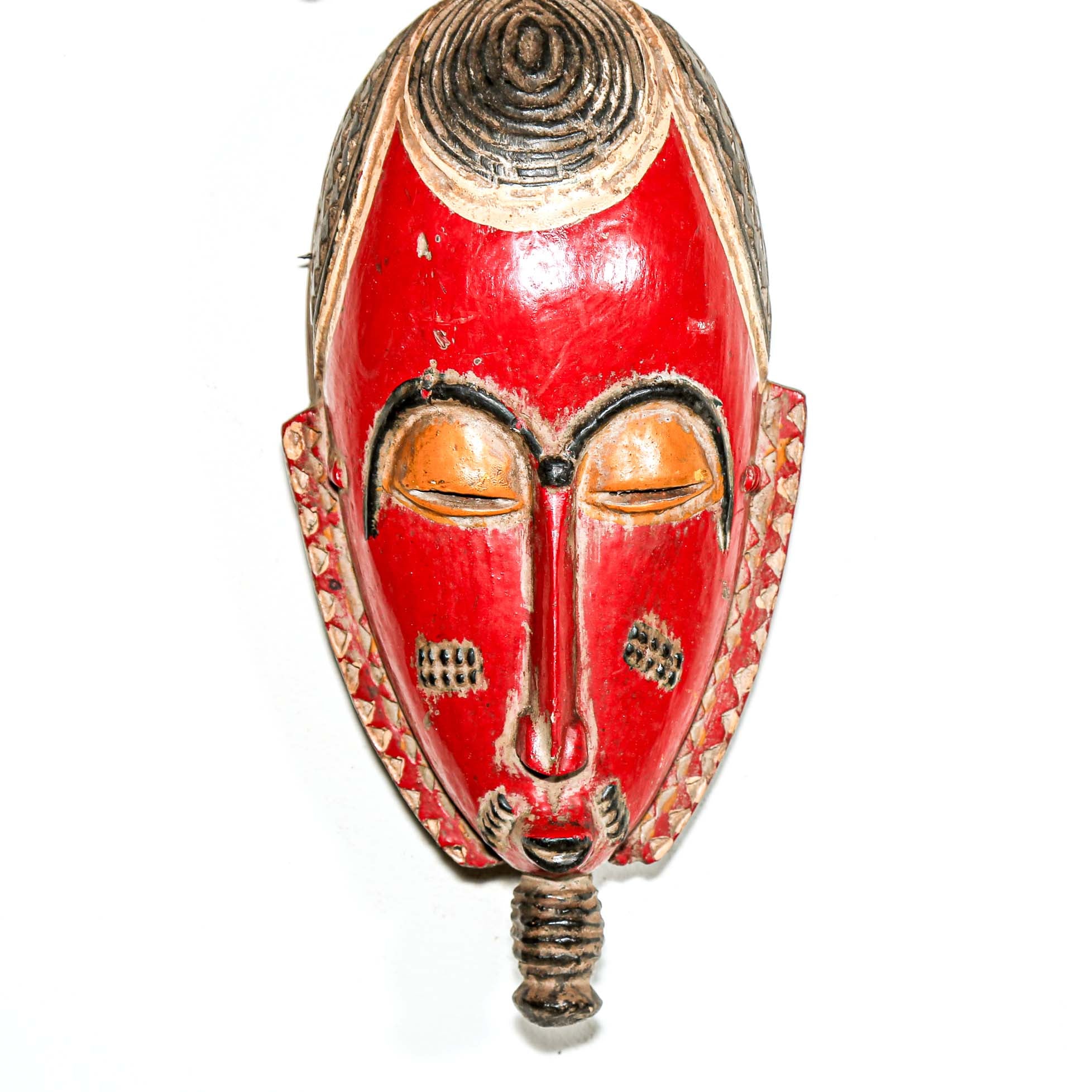 Red wooden mask with intricate carvings on a white background