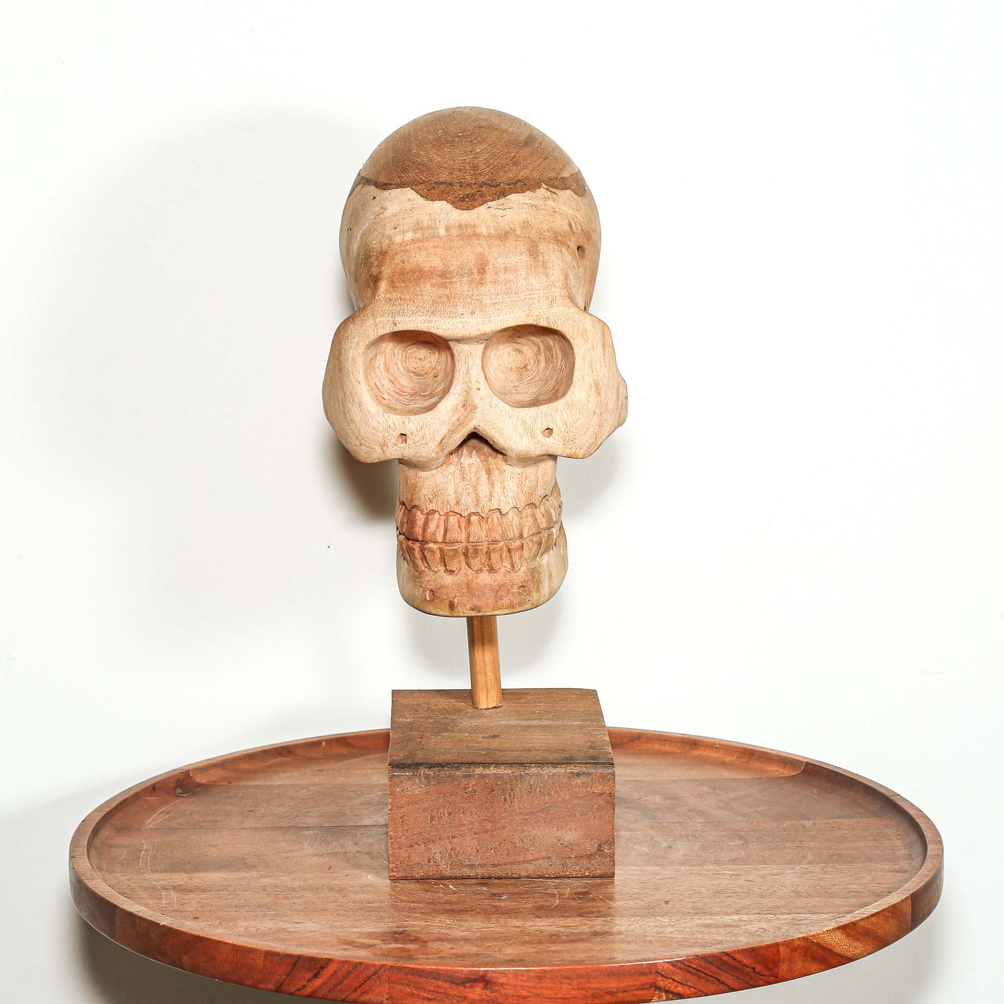 Hand Carved African Wooden human skull sculpture on a wooden base in a living room on a side table