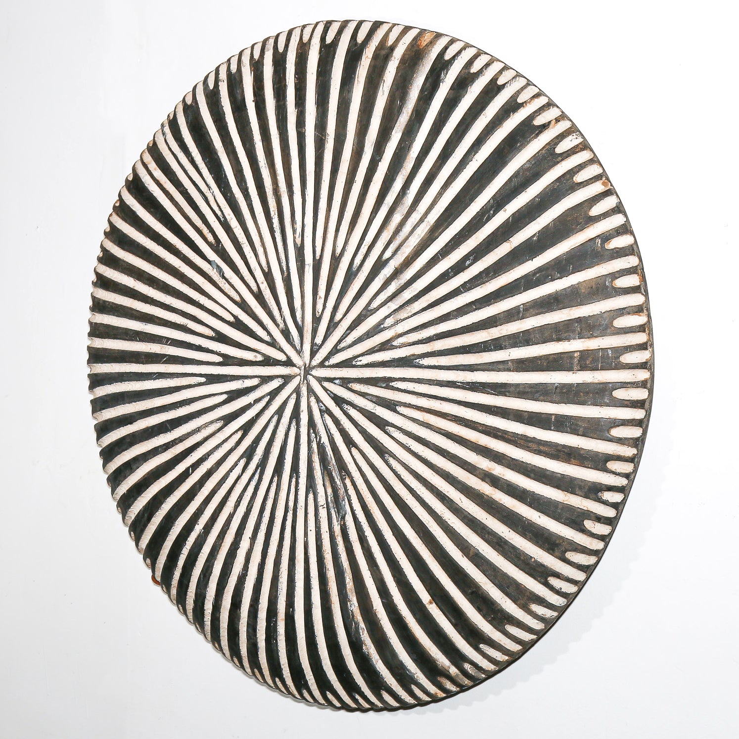Round wood African art wall hanging for sale with black and white striped pattern on a white background living room design