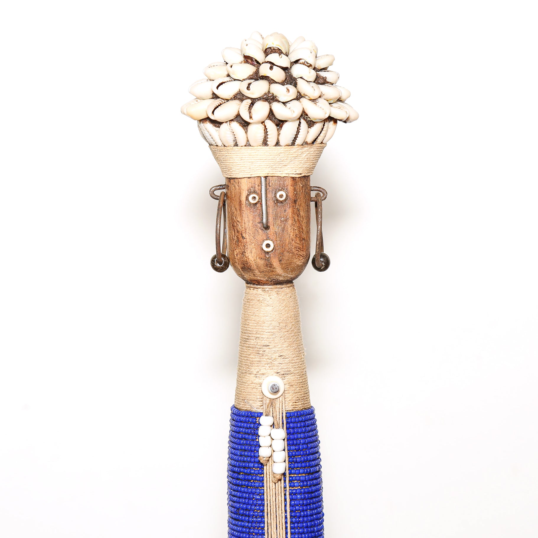 A handmade African-style wooden doll sculpture with a woven beige body, blue beaded skirt, and a crown of white cowrie shells, set against a plain white background.