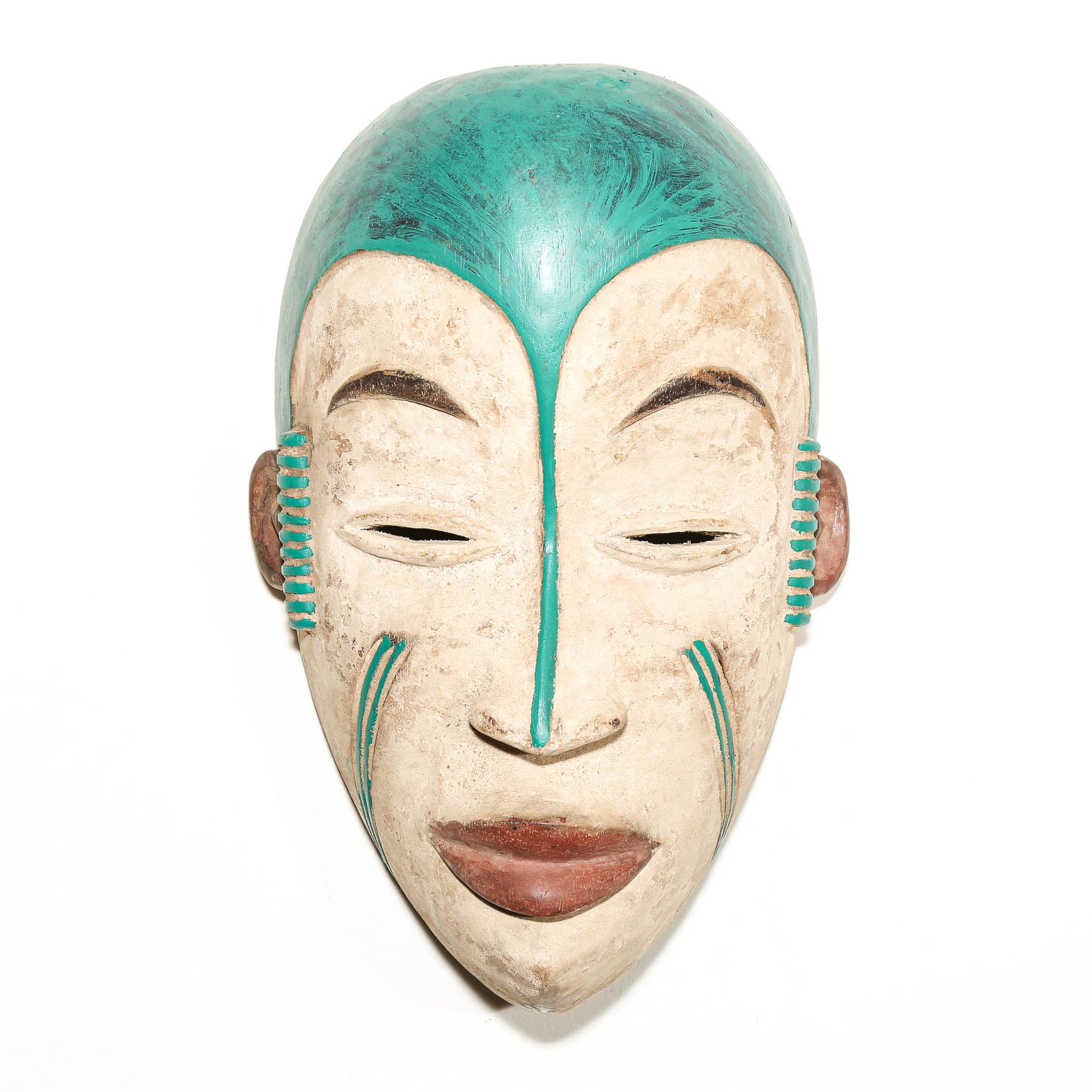 A carved wooden African-style mask with a weathered beige face, painted turquoise hair, and turquoise and brown decorative accents on the cheeks and ears, shown against a plain white background.